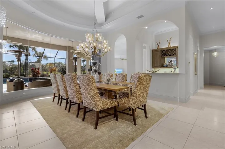 Tiled dining space with a high ceiling, a tray ceiling, ornamental molding, and a chandelier