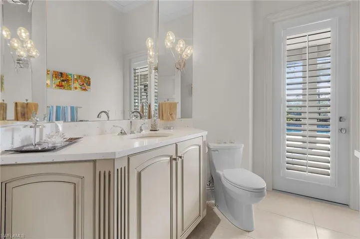 Bathroom with vanity, toilet, tile patterned floors, and crown molding