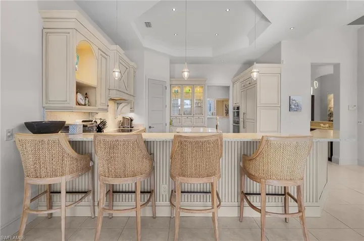Kitchen featuring kitchen peninsula, hanging light fixtures, a kitchen bar, and a tray ceiling