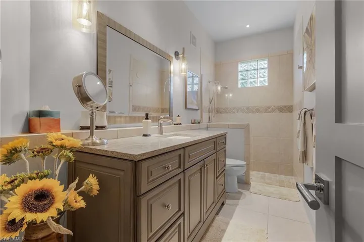 Bathroom with vanity, toilet, a tile shower, and tile patterned flooring