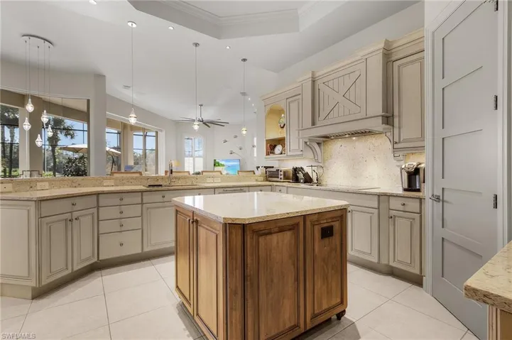 Kitchen featuring kitchen peninsula, a raised ceiling, decorative light fixtures, sink, and a center island