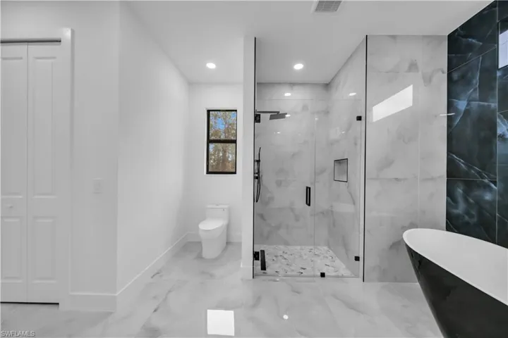 Full bath featuring a freestanding tub, a marble finish shower, marble finish flooring, a closet, and recessed lighting