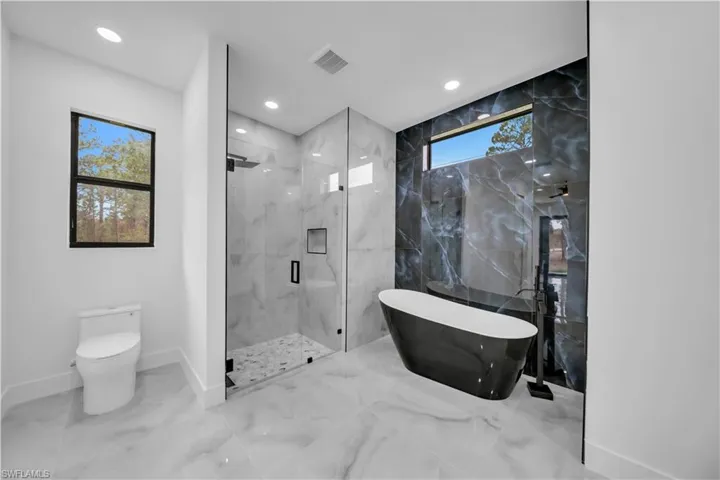 Full bath featuring a marble finish shower, a freestanding bath, recessed lighting, and marble finish floors