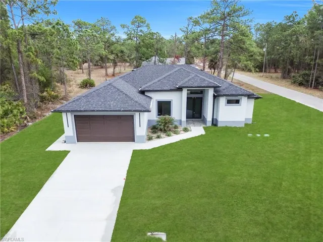 View of front of home featuring a front lawn, stucco siding, and concrete driveway