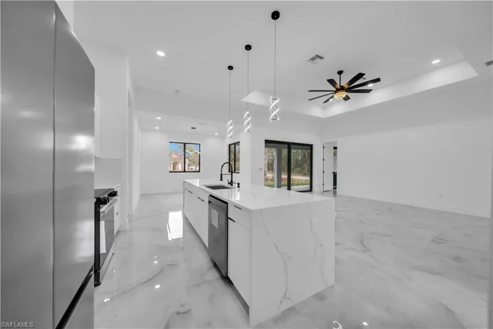 Kitchen with modern cabinets, stainless steel appliances, light marble finish floors, white cabinetry, and pendant lighting