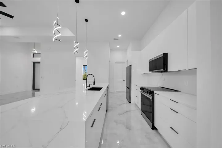 Kitchen with modern cabinets, white cabinetry, and stainless steel appliances