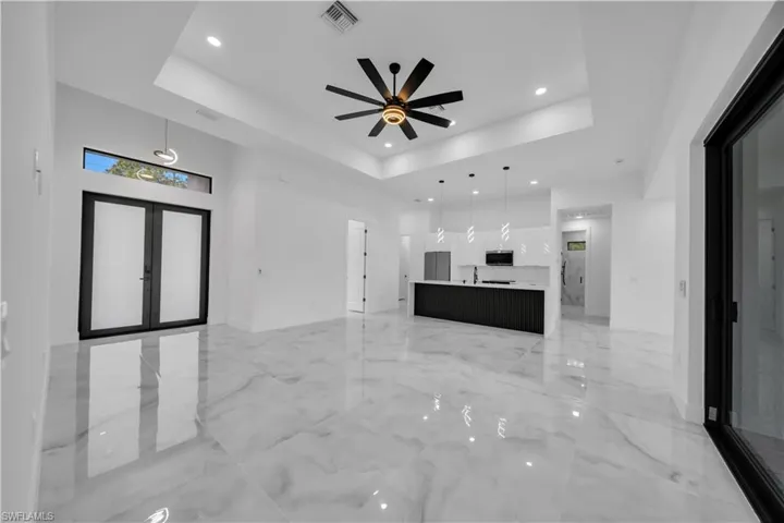 Unfurnished living room with french doors, a ceiling fan, recessed lighting, a high ceiling, and light marble finish floors