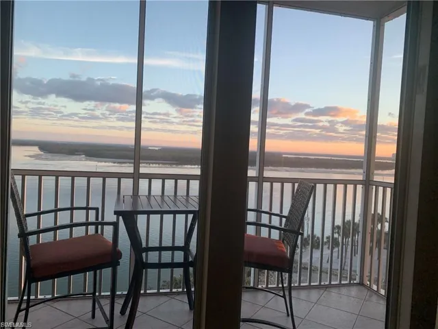 Balcony at dusk with a sunroom and a water view