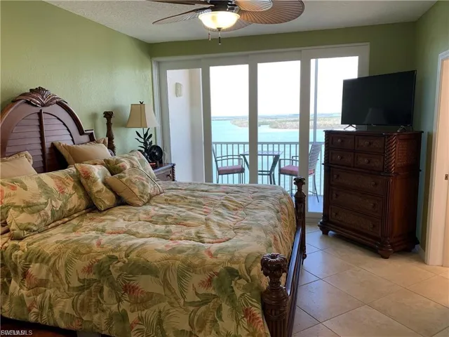 Bedroom featuring access to exterior, light tile patterned flooring, a textured ceiling, and ceiling fan