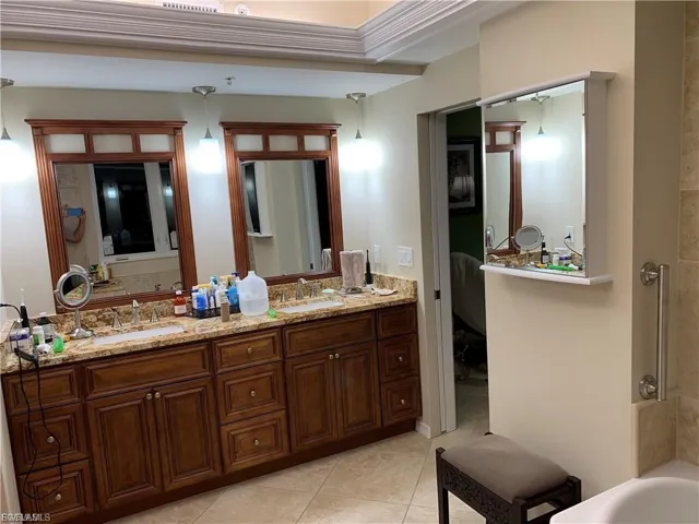 Ensuite bathroom with a tub, double vanity, and light tile patterned flooring