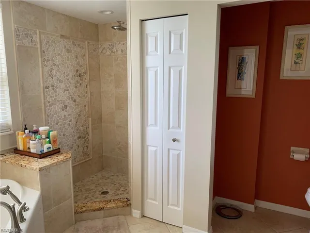 Bathroom with a bath, light tile patterned flooring, a tile shower, and a closet
