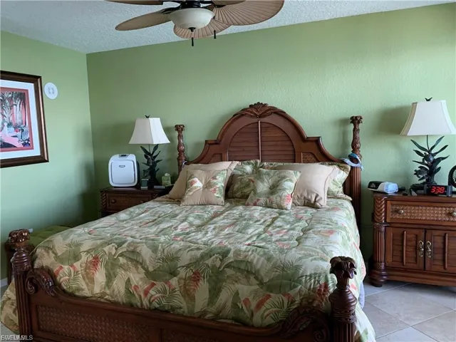 Bedroom with a textured ceiling, a ceiling fan, and tile patterned flooring
