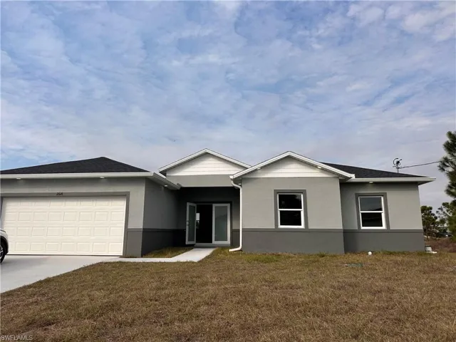Ranch-style home with concrete driveway, stucco siding, a front yard, and a garage