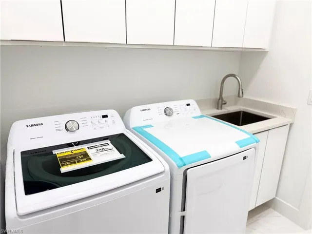 Laundry room featuring cabinet space, light marble finish flooring, and separate washer and dryer
