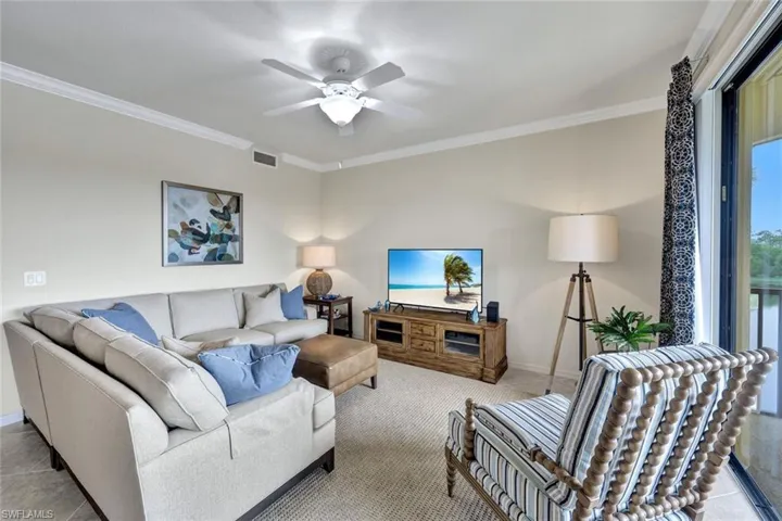 Carpeted living room with ornamental molding and a ceiling fan