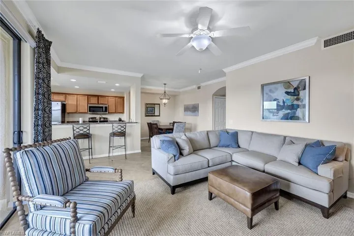 Living room with crown molding, arched walkways, recessed lighting, a ceiling fan, and light tile patterned floors