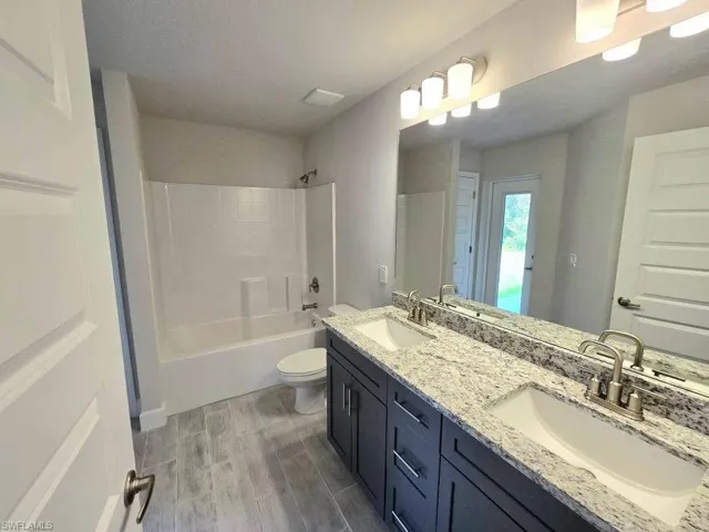 2nd/Pool bathroom with double vanity, bathtub / shower combination, wood finished floors, and toilet