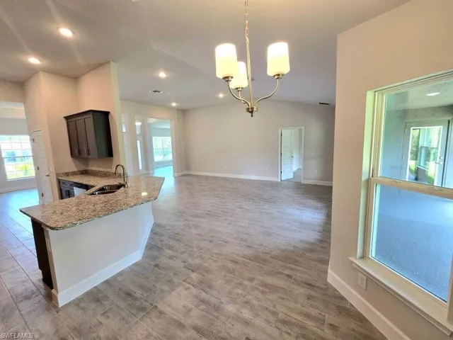 Kitchen with plenty of natural light, a sink, light stone countertops, a chandelier, and recessed lighting