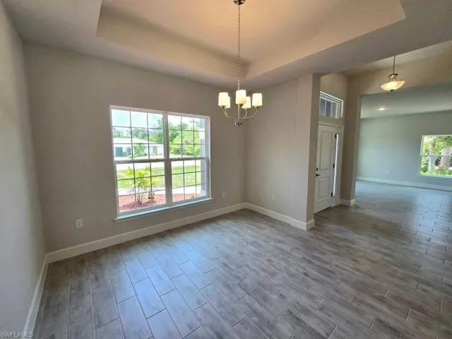 Dining room featuring a raised ceiling, baseboards, and wood finished floors