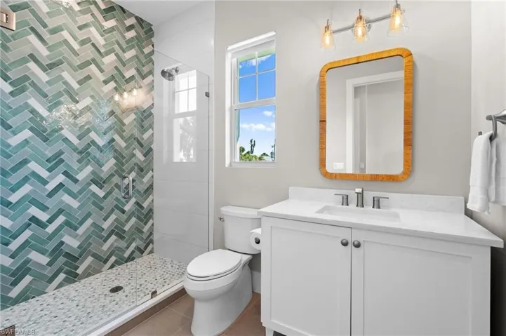 Full bath with vanity, toilet, and a tile shower. virtually edited photo