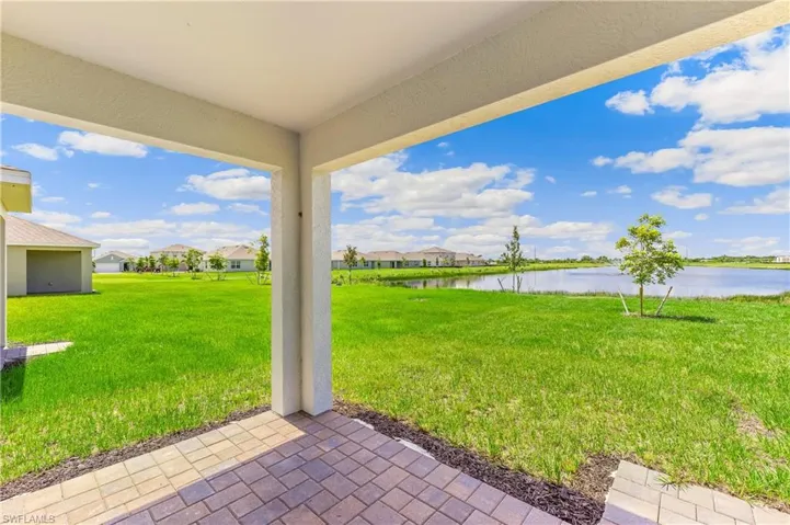 View of green lawn with a water view, a patio area, and a residential view