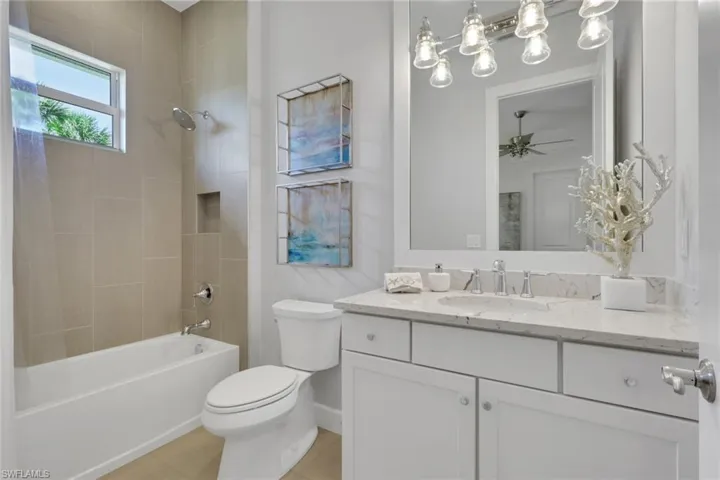 Bathroom with vanity, shower / tub combo with curtain, a ceiling fan, and light tile patterned floors