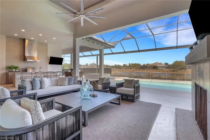 View of patio with an outdoor kitchen with living area, a sunroom, a lanai, an outdoor pool, and a ceiling fan