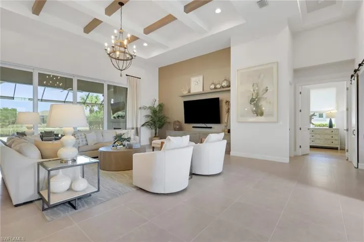 Living room featuring a barn door, coffered ceiling, a chandelier, plenty of natural light, and light tile patterned floors