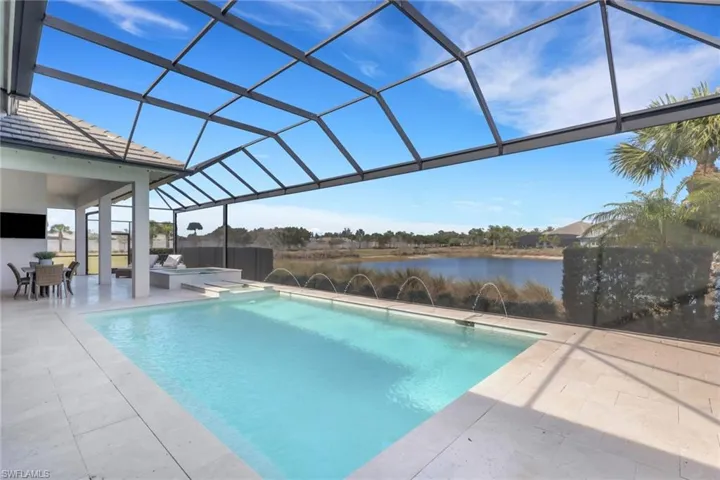 Outdoor pool with a sunroom, glass enclosure, a patio area, outdoor dining area, and a water view