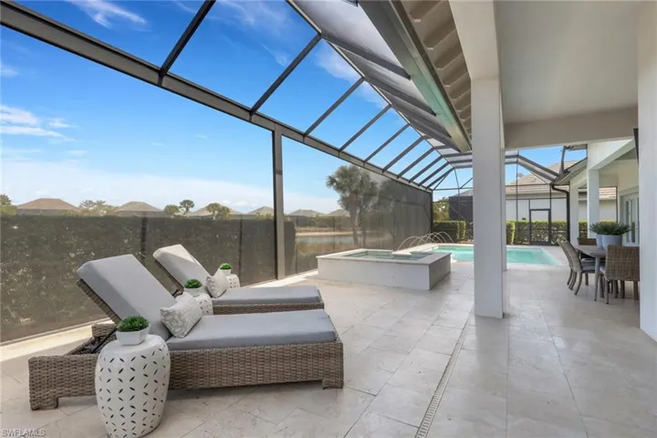 View of patio with a sunroom, a lanai, a pool with connected hot tub, outdoor dining space, and a water view