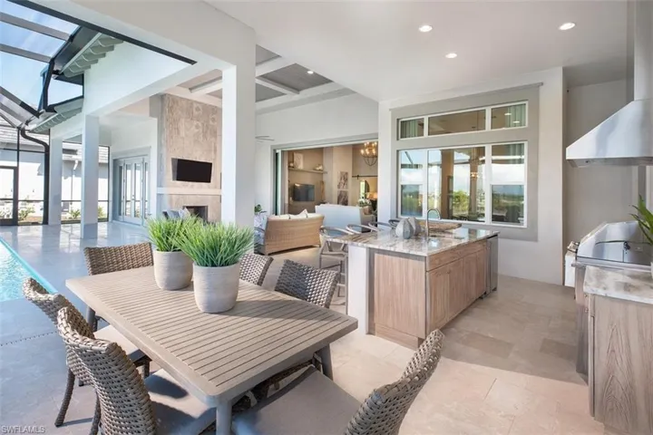View of patio with a fireplace, french doors, a lanai, and an outdoor kitchen / dining area