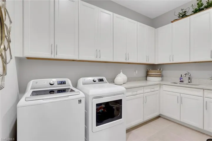 Laundry room featuring separate washer and dryer, light tile patterned floors, and cabinet space