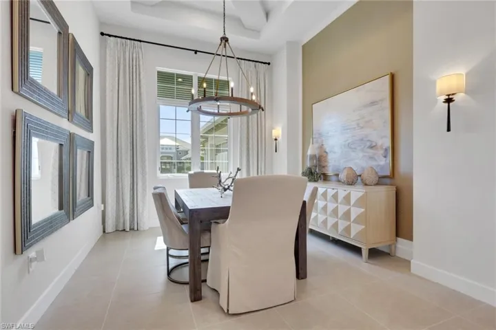 Dining space with a tray ceiling, light tile patterned flooring, and a chandelier