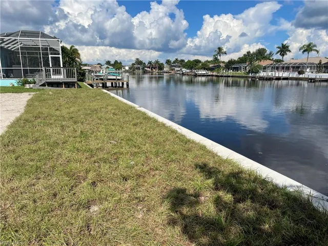 View of dock with a yard and a water view