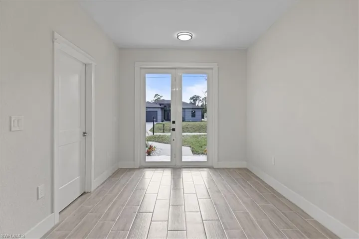 Interior space featuring wood-finish tile flooring, white-panel interior door, and French-style glass doors