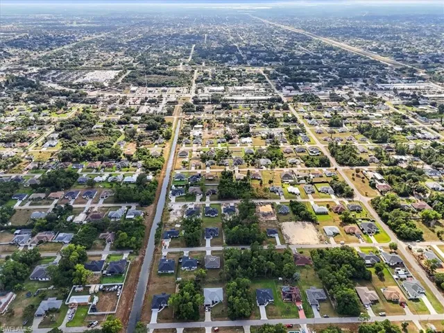 Aerial perspective of a developed residential grid featuring paved streets, mature trees, suburban lot distribution, and proximity to regional infrastructure