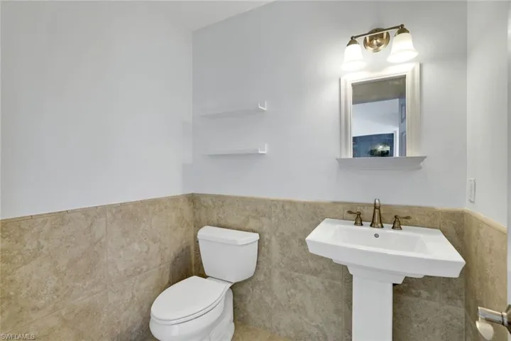 Half bathroom featuring a wainscoted wall and tile walls