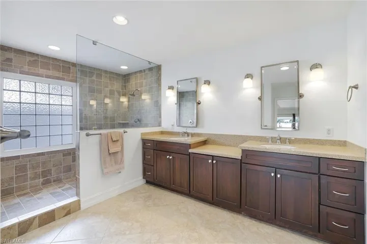Bathroom with double vanity, a walk in shower, light tile patterned floors, and recessed lighting