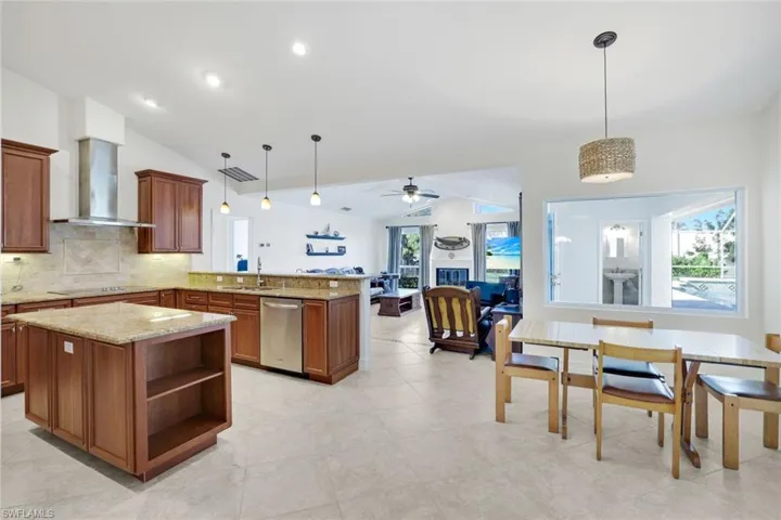 Kitchen featuring lofted ceiling, decorative light fixtures, open floor plan, a peninsula, and a center island