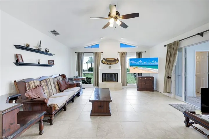 Living room featuring a ceiling fan, light tile patterned flooring, and a glass covered fireplace