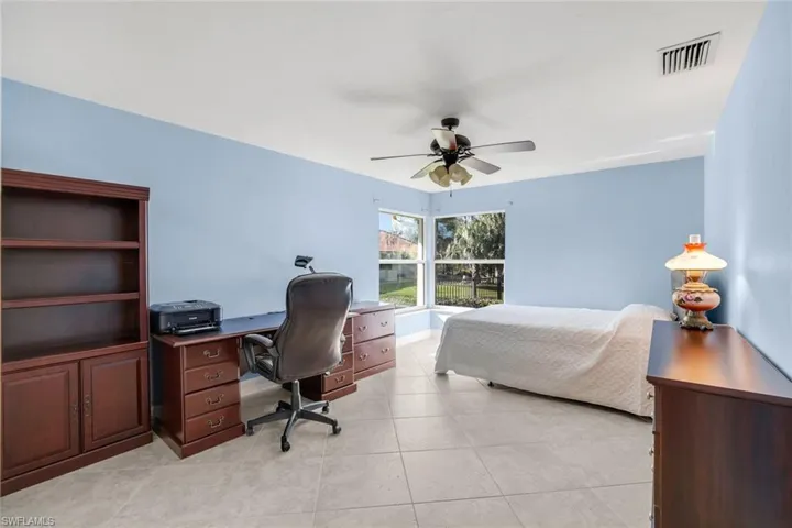 Bedroom featuring a desk, ceiling fan, and light tile patterned flooring