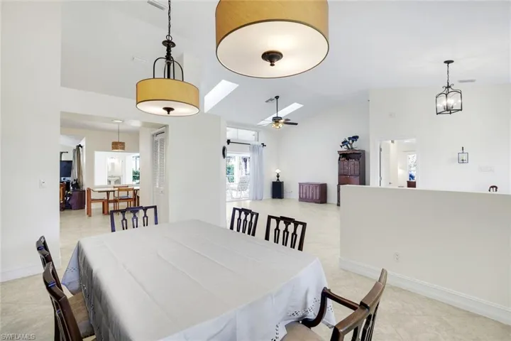 Dining area featuring a skylight, vaulted ceiling, ceiling fan, and light tile patterned floors