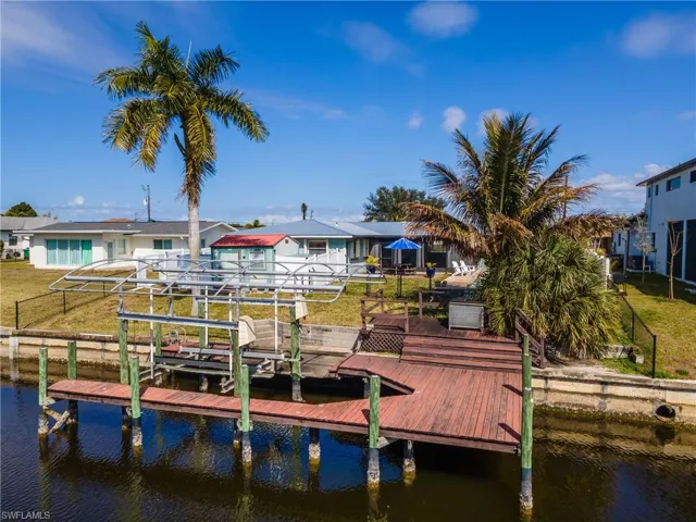 Dock area featuring a water view, boat lift, and a yard