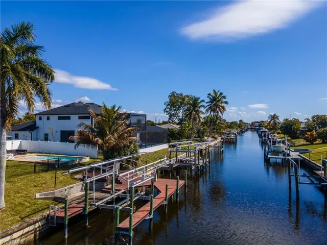 Dock area with boat lift, a water view, and a yard