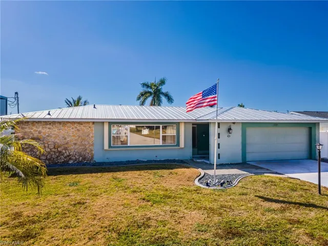 View of front of property featuring stucco siding, a front yard, driveway, and an attached garage