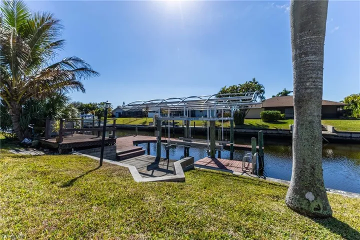 Dock featuring boat lift, a water view, and a yard