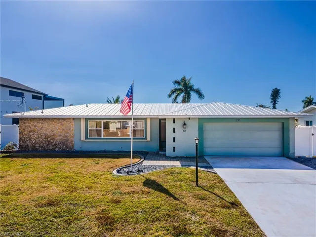 View of front of home with stucco siding, a front yard, concrete driveway, and an attached garage