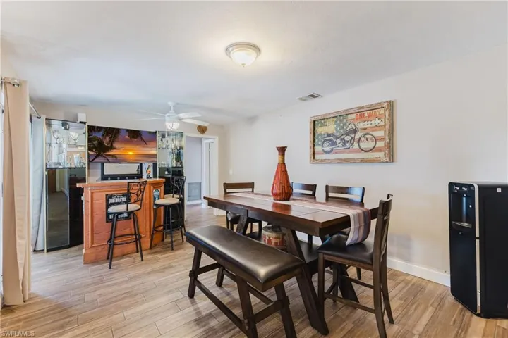 Dining area with light wood-type flooring, a ceiling fan, and bar area