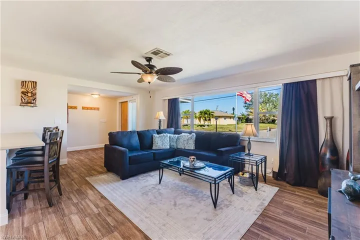 Living room with a ceiling fan and dark wood-type flooring