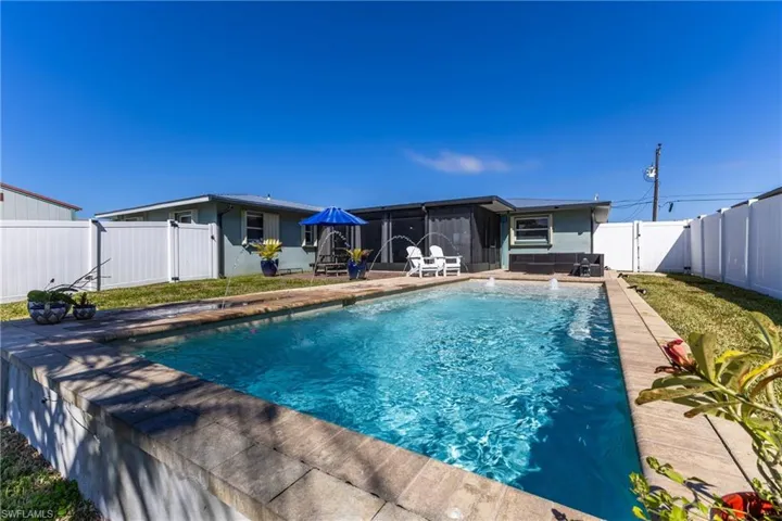 View of pool featuring a fenced backyard, a sunroom, and patio surround